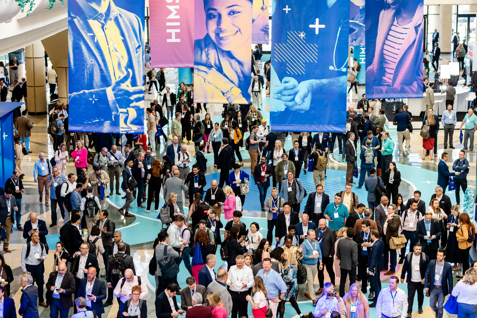 A crowd of conferencegoers under banners emblazoned with the HIMSS24 logo.