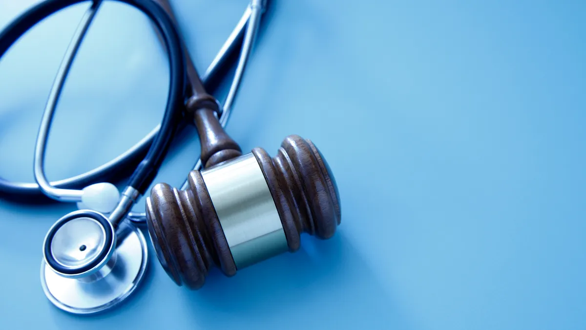 A gavel and a stethoscope sit on a blue background.