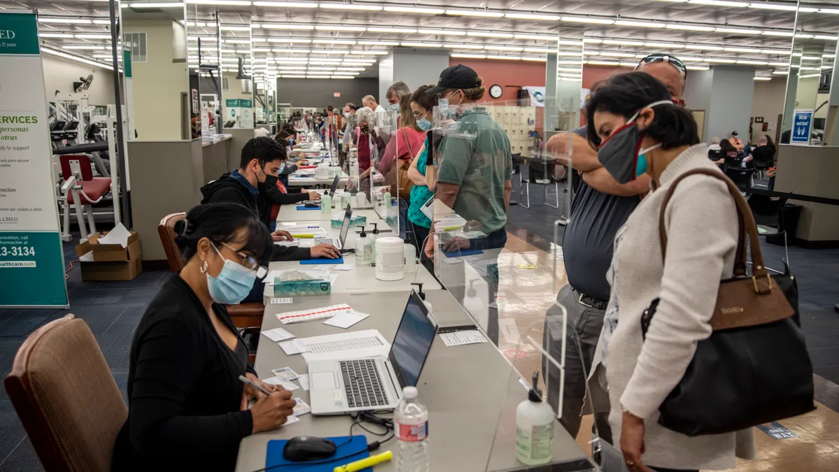 Patients wait to check-in at a line of kiosks to get vaccinated.