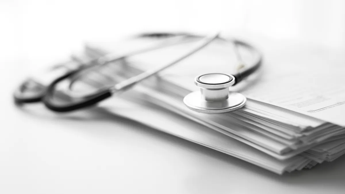 A stethoscope resting on a stack of white papers