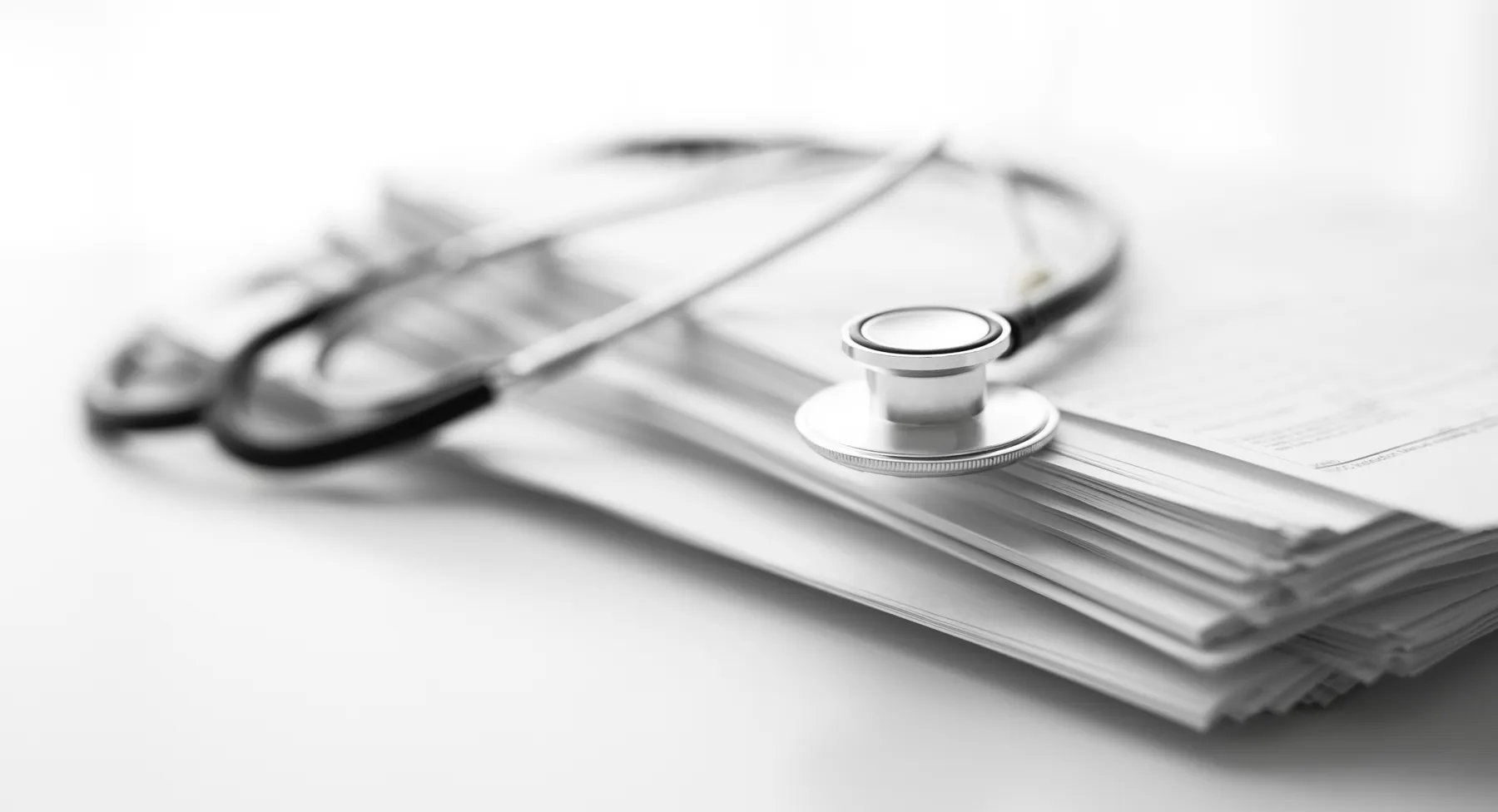 A stethoscope resting on a stack of white papers