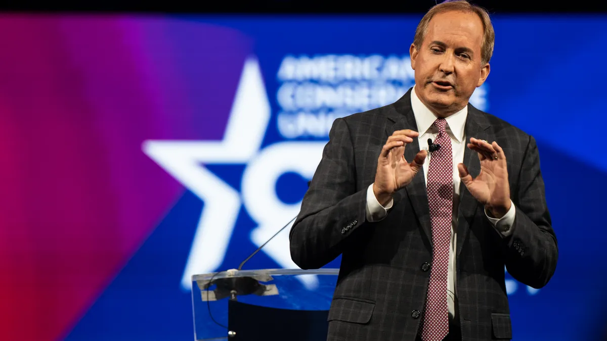 Ken Paxton giving a speech with both of his hands raised in front of his chest