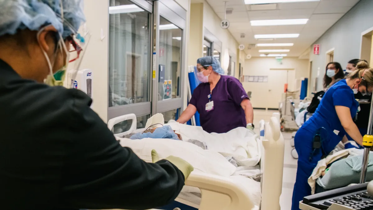 Two emergency room nurses wheel a patient on a gurney through a hospital hallway.