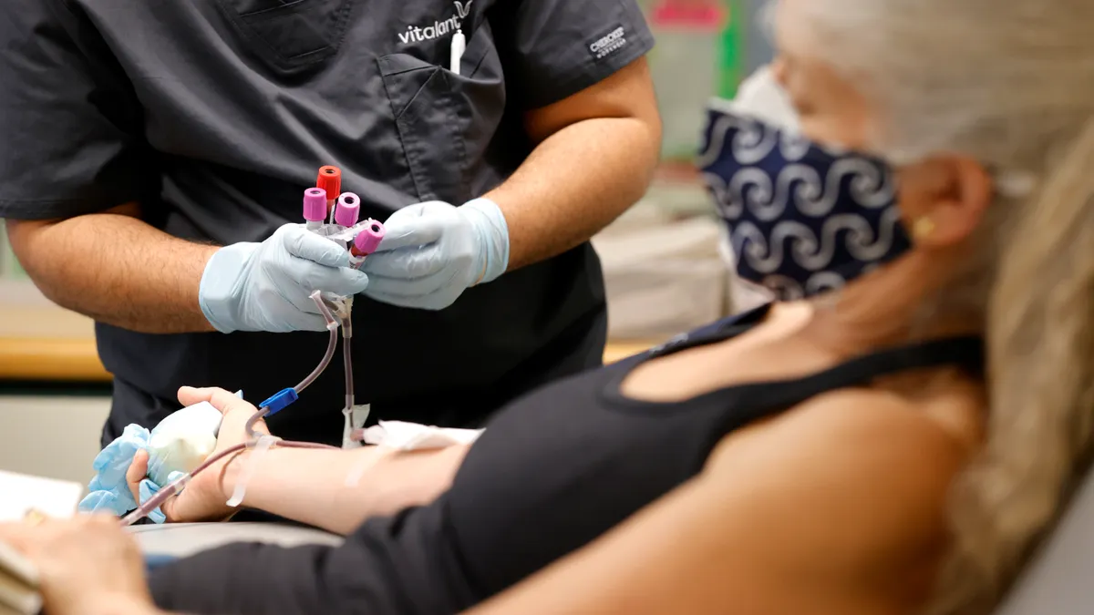 A phlebotomist collect vials of blood from an intravenous line from a patient who is donating blood at Vitalant blood donation center on January 11, 2022 in San Francisco, California.