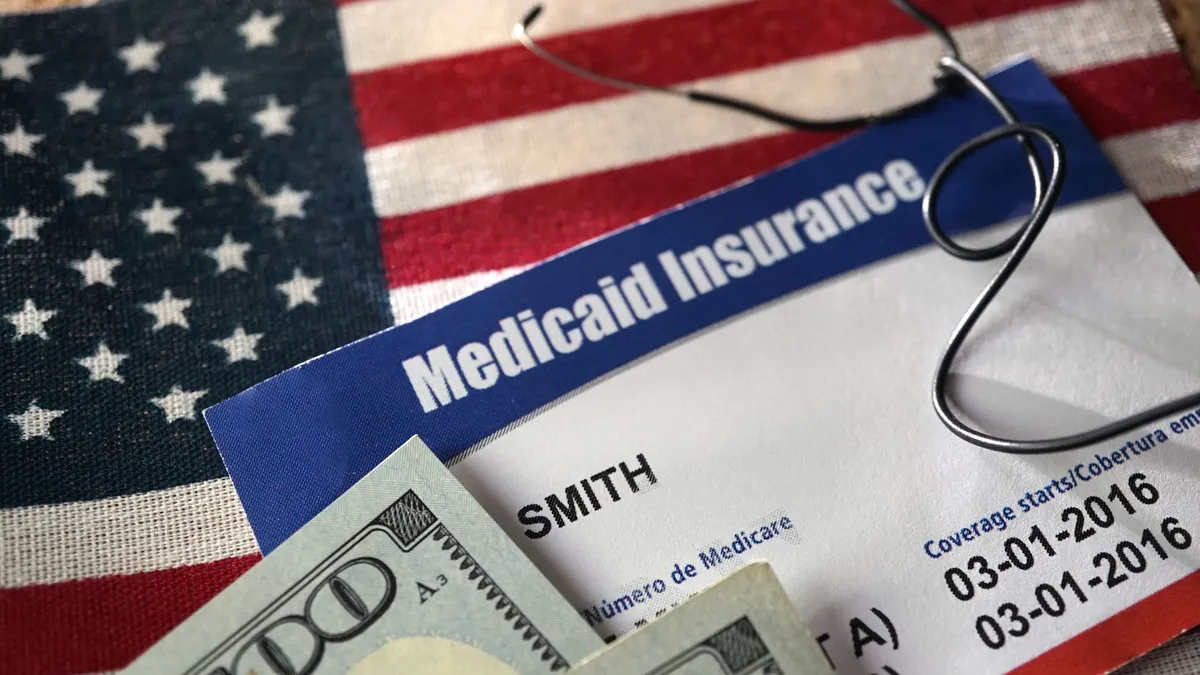 a medicaid insurance card on top of a small American flag