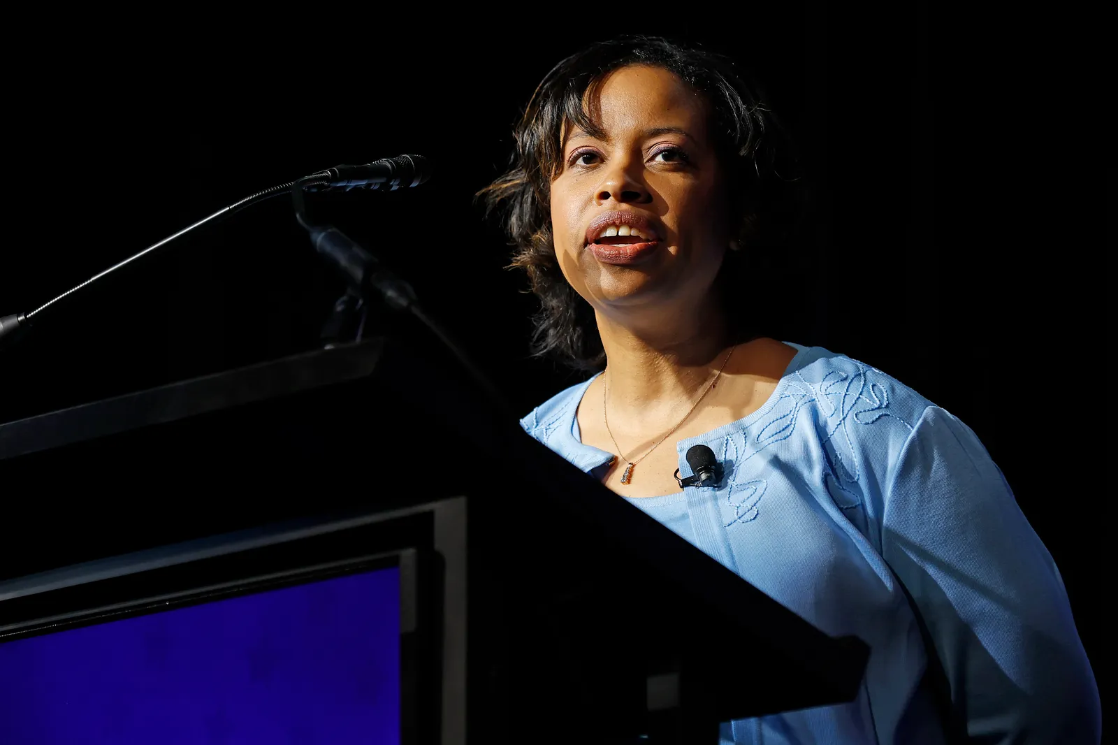 Chiquita Brooks-LaSure speaks behind a podium in front of a black background.