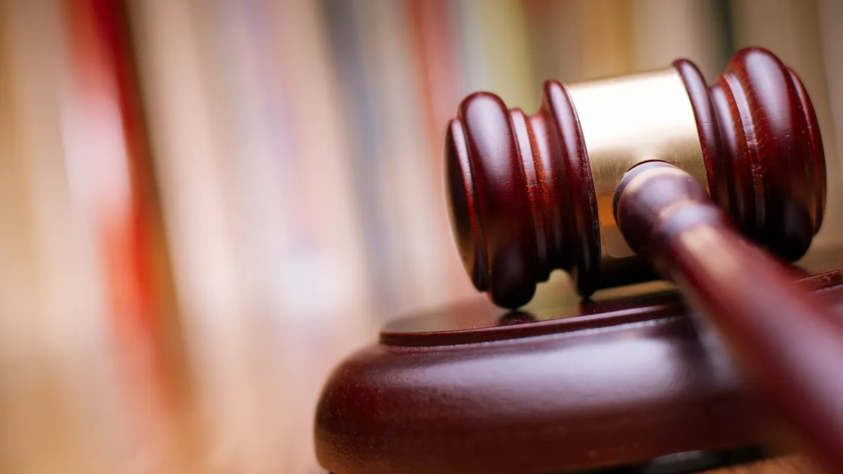 Close up shiny wooden law gavel in dark brown color on top of a wooden table in an office.