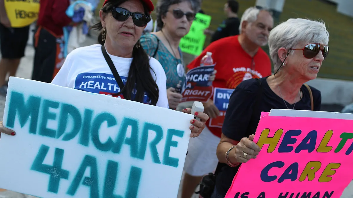 protestors hold up signs advocating for universal healthcare