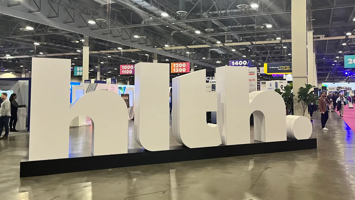 HLTH attendees walk the exhibition floor around the conference's logo onsite in Las Vegas.