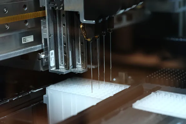 A machine moves between several rows of test tubes.